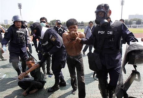 Thajská policie odvádí zadrené demonstranty ze sportovního stadionu v Bankoku.