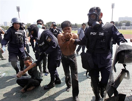 Thajská policie odvádí zadržené demonstranty ze sportovního stadionu v Bankoku.