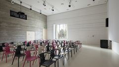 Multifunkní hlavní sál s velkým tvercovým oknem zasazeným v líci fasády.