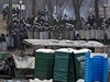 Policisté v ulicích Kyjeva. Kovovými títy se chrání proti demonstrantm, ti zas stavjí barikády.