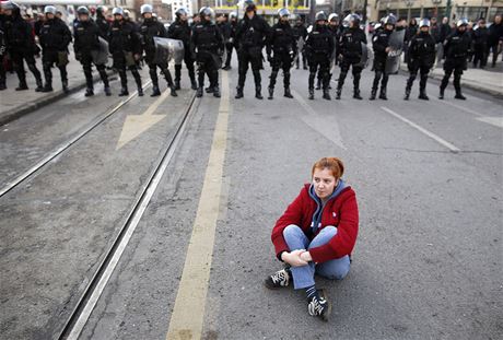 Protivldn demonstrantka sed na ulici Sarajeva, v pozad policejn kordon.