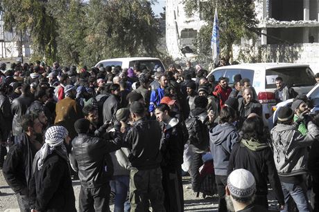 Obyvatelé Homsu ekají u vozidel OSN a erveného plmsíce na evakuaci.