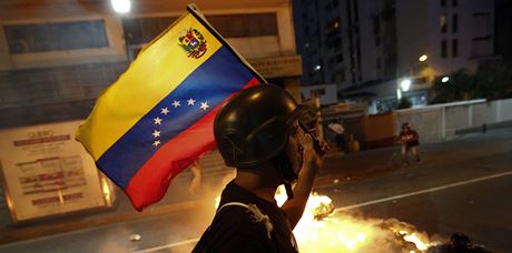 Opoziční demonstrant nese venezuelskou vlajku
