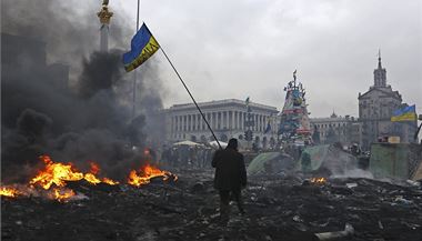 Demonstrant s ukrajinskou vlajkou na troskch splench barikd na Majdanu.