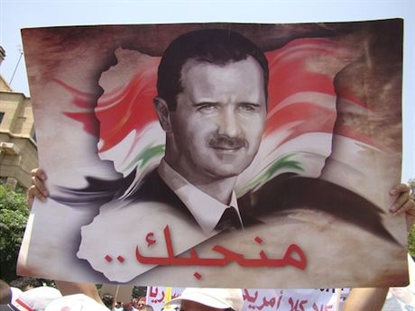 Příznivci syrského prezidenta Bašára Asada s jeho portrétem nad hlavami protestují před americkou ambasádou v Damašku 11. července.