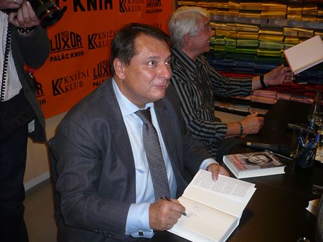 Jiří Paroubek podepisuje své aktuální knižní dílo Plnou parou v politice. Vedle u stolu kmotr knihy Jiří Krampol.