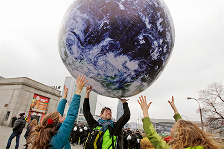 Ekologití aktivisté si bhem klimatického summitu OSN ve Varav hrají s modelem zemkoule.