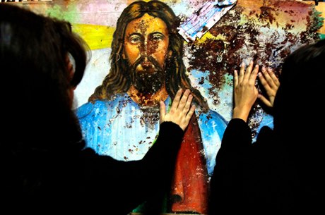 Věřící se dotýkají zkrvaveného obrazu Ježíše Krista v koptském ortodoxním chrámu v Alexandrii, před nímž 1. ledna při bombovém atentátu zahynulo 23 lidí a na sto bylo zraněno.