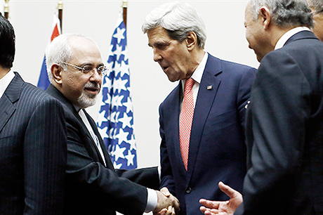 Íránský ministr zahraničí Mohammad Džavád Zaríf (vlevo) a jeho americký protějšek John Kerry si podávají ruce během ženevského jednání Íránu a šesti mocností (stálí členové Rady bezpečnosti OSN a Německo).