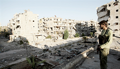 Bojovník opoziční Svobodné syrské armády pozoruje 12. srpna poškozené budovy a trosky na ulici předměstí severosyrského města Aleppo.