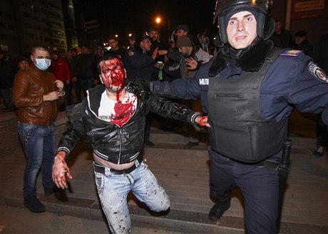 Policista vyvádí zranného demonstranta. V Doncku se stetla proruská skupina demonstrant se skupinou odsuzující ruské aktivity na Krymu. Jeden lovk byl zabit.
