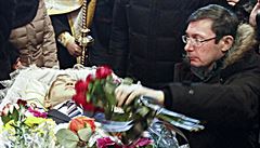 Jurij Lucenko klade kytici na rakev zabitého demonstranta.