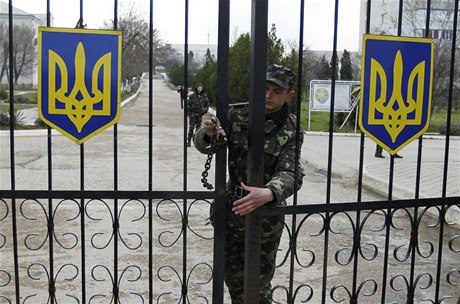 Ukrajinský voják zamyká bránu letecké základny v krymském Belbeku.