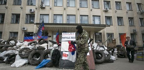 Proruský ozbrojenec ped zabarikádovanou budovou místní vlády v Kramatorsku