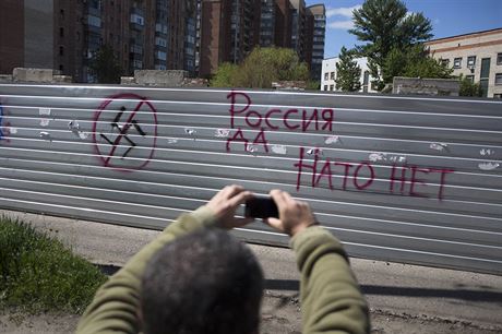 "Rusko ano, NATO ne." Muž si fotí graffiti na zdi ve Slavjansku.