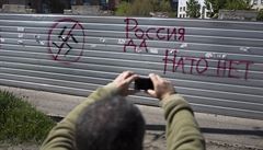 "Rusko ano, NATO ne." Muž si fotí graffiti na zdi ve Slavjansku.