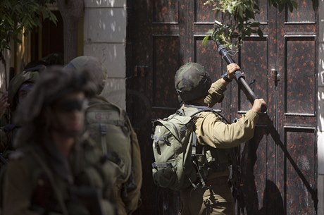 Izraeltí vojáci rozbíjejí zámek na dveích jednoho z palestinských dom poblí...