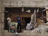Palestinci stojí v pokozeném dom vedle obrazu Jásira Arafata.