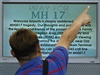 Divák ukazuje na tabuli s modlitbou za obti letu MH 17 na mezinárodním...