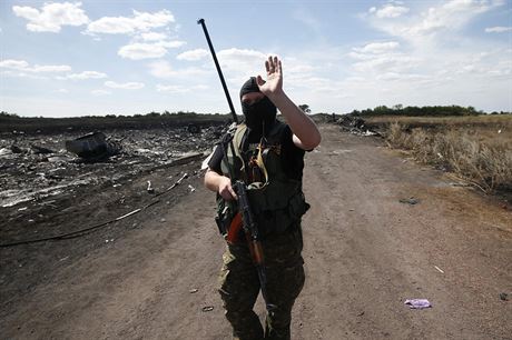 Ozbrojený separatista gestikuluje na novináe na míst zícení letu MH17.