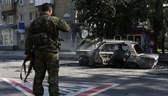 Ukrajinský separatista pozoruje vrak auta po bombardování vládními silami