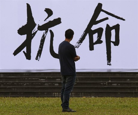 Volby v Hongkongu v reii íny - aktivista sleduje nápis odpor.