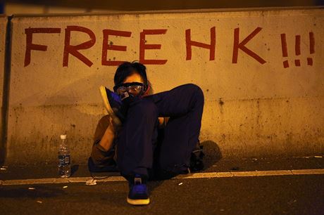 Demonstrant v plynov masce sed u npisu Svobodn Hongkong. Kvli astmu...