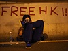 Demonstrant v plynové masce sedí u nápisu Svobodný Hongkong. Kvli astému...