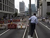Byznysmen ve finanní tvrti Hongkongu sledují pouliní zátarasy, vztyené...