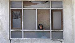Afghánská holčička vykukuje z okna poničeného při atentátech před inaugurací...
