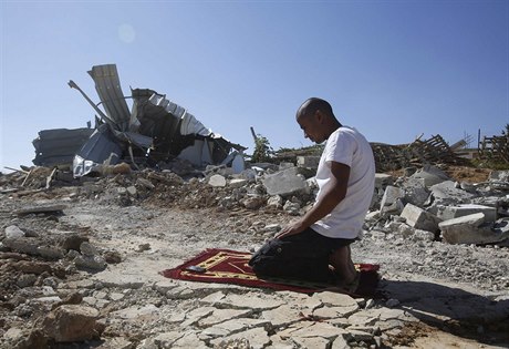 Palestinský beduín se modlí u trosek domu, který mu zboil izraelský buldozér.