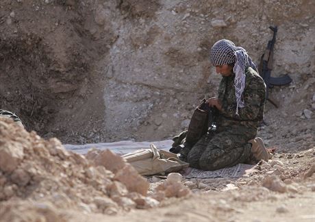 Kurdská bojovnice kontroluje na frontové linii svou  výbavu. V adách kurdských...