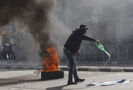 Palestinský protestant polévá izraelskou vlajku holavinou.
