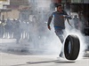 Palestinec posílá pneumatiku vstíc kordonu izraelských policist.