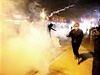 Demosntranti utíkají ped slzným plynem, který po nich pálí policie ve...