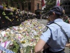 Policistka stojí ped záplavou kvtin, které pipomínají památku tragédie v...