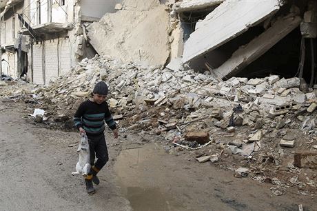 Chlapec s krlkem v ruce prochz rozbombardovanou ulic Aleppa.