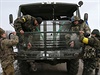 Ukrajintí vojáci opravují rozbité pední sklo svého vozidla.