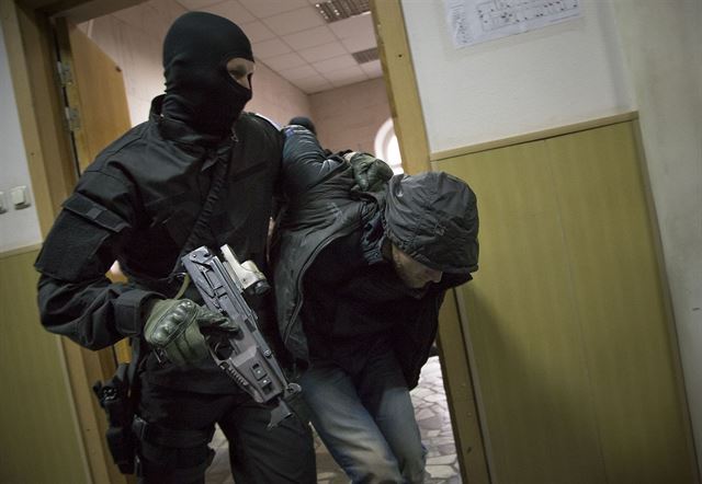 Policista pivádí jednoho z podezelých do soudní sín.