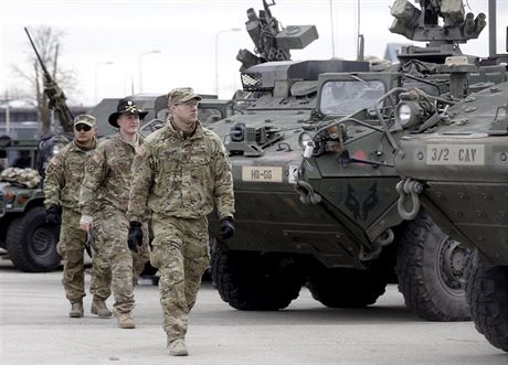 Amerití vojáci prochází kolem obrnných trasport Stryker.