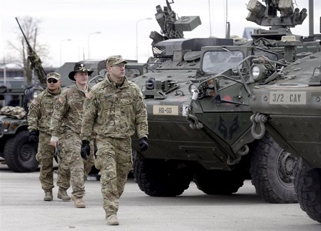 Američtí vojáci prochází kolem obrněných trasportů Stryker.