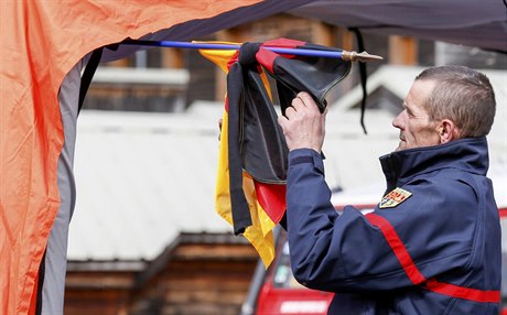 Francouzský hasi váe ernou smutení stuhu na nmeckou vlajku...