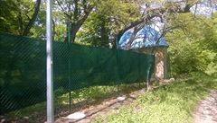 Kolem bývalého squatu vyrostl zelený plot s ostnatým drátem.