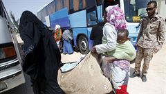 Migranti přenášejí svůj skromný majetek do autobusů, které je svážejí do...