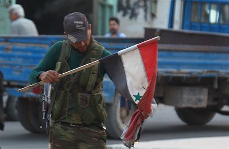 Ozbrojenec z al-kaidistické Fronty an-Nusra s roztrhanou syrskou vlajkou.