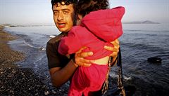 Syrský uprchlík vyndavá dít z lodi.