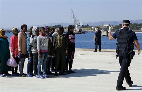 Policista dohlíží na nově příchozí uprchlíky