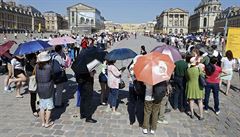 Na zámku ve Versailles se turisté ped sluncem chrání detníky.