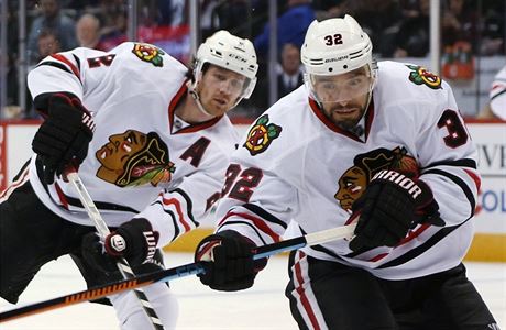 Obránce Chicago Blackhawks Michal Rozsíval vyráí k puku, zatímco center...