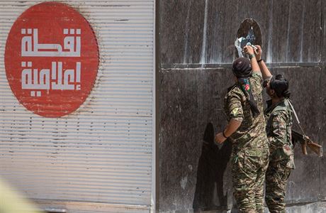 Kurdtí vojáci strhávají plakát Islámského státu.